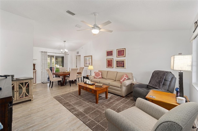 living room with a textured ceiling, ceiling fan with notable chandelier, dark hardwood / wood-style floors, and lofted ceiling