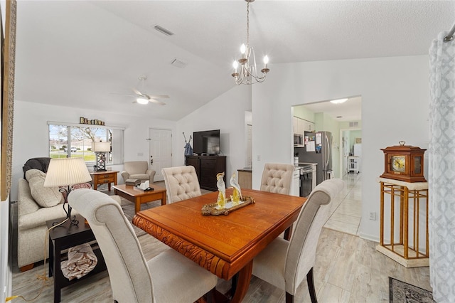 dining room featuring ceiling fan with notable chandelier, light hardwood / wood-style floors, and vaulted ceiling