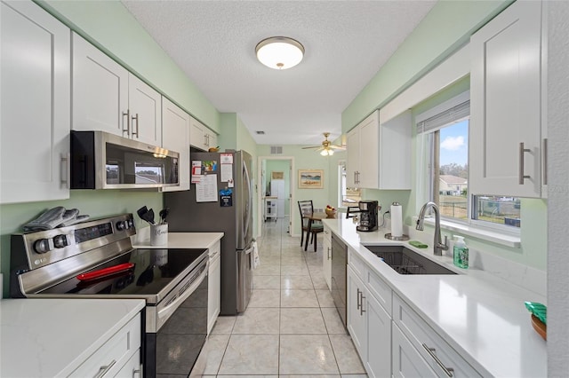 kitchen featuring white cabinetry, sink, ceiling fan, stainless steel appliances, and a textured ceiling