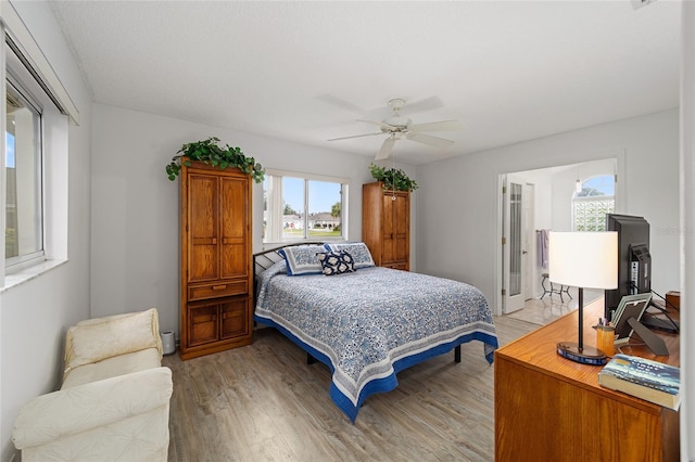 bedroom with ceiling fan, multiple windows, and light hardwood / wood-style flooring