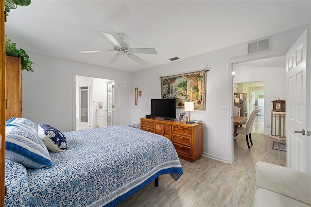 bedroom with ceiling fan, light wood-type flooring, a textured ceiling, connected bathroom, and stainless steel refrigerator