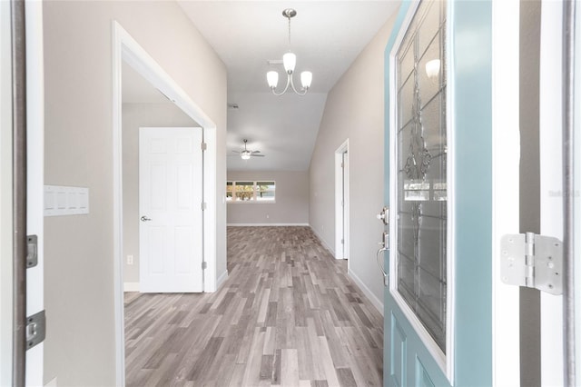 hallway with a chandelier, lofted ceiling, and light wood-type flooring