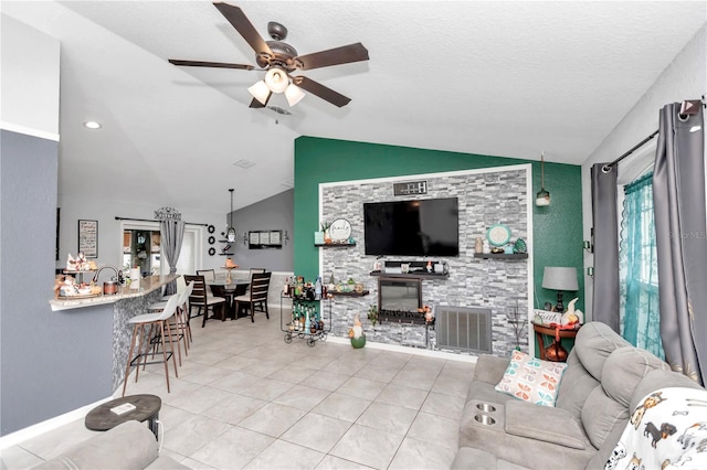 tiled living room with a fireplace, a textured ceiling, vaulted ceiling, and ceiling fan