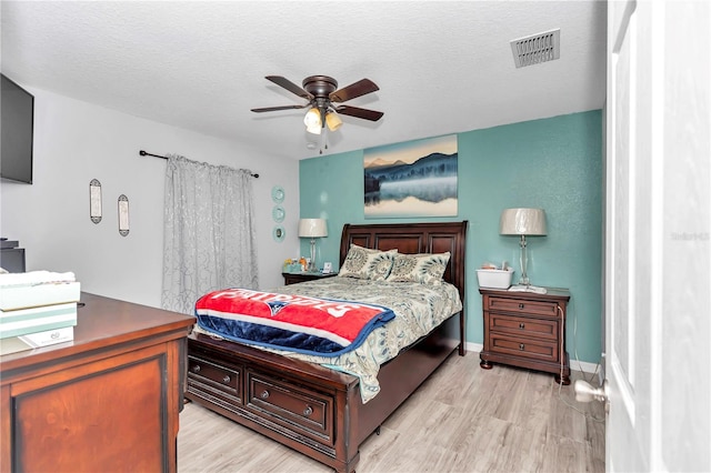 bedroom featuring ceiling fan, light hardwood / wood-style floors, and a textured ceiling