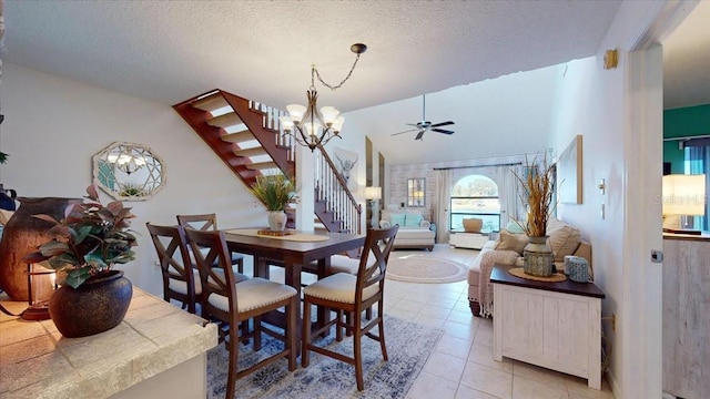 dining space featuring a textured ceiling, ceiling fan with notable chandelier, light tile patterned flooring, and vaulted ceiling