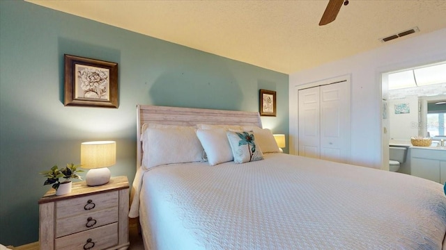 bedroom with ceiling fan, a closet, ensuite bathroom, and a textured ceiling