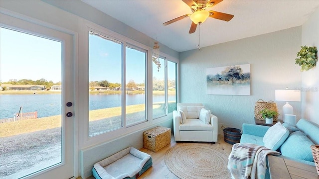 sunroom / solarium featuring ceiling fan, plenty of natural light, and a water view