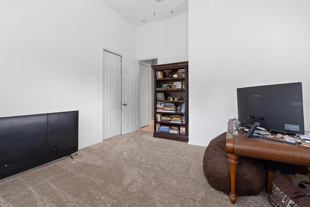 office featuring light colored carpet and a towering ceiling