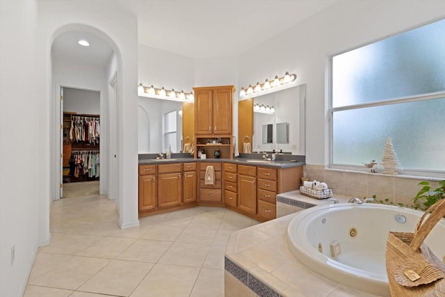 bathroom featuring tile patterned floors, vanity, and a relaxing tiled tub