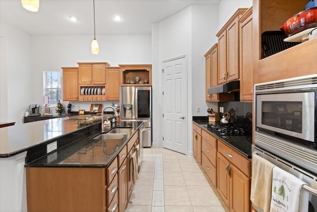 kitchen with sink, light tile patterned floors, an island with sink, decorative light fixtures, and stainless steel appliances