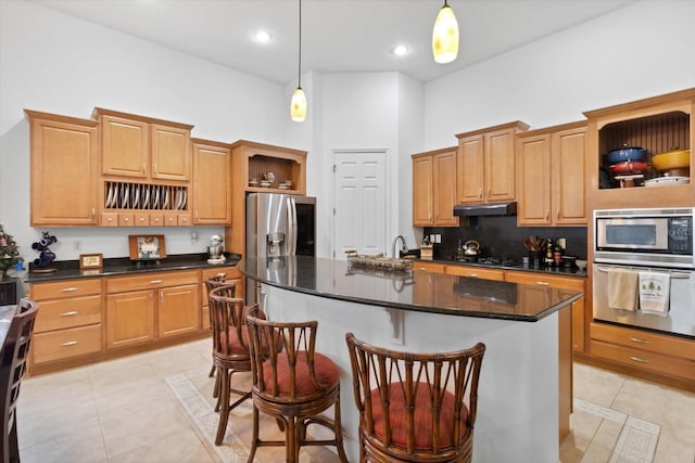 kitchen with appliances with stainless steel finishes, a center island with sink, light tile patterned floors, and pendant lighting