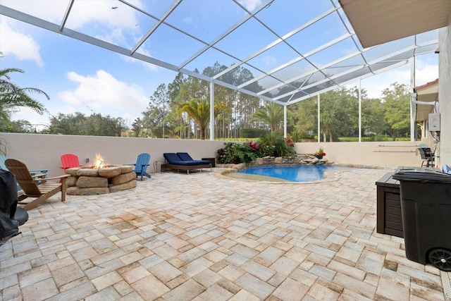 view of pool with a patio, glass enclosure, and an outdoor fire pit