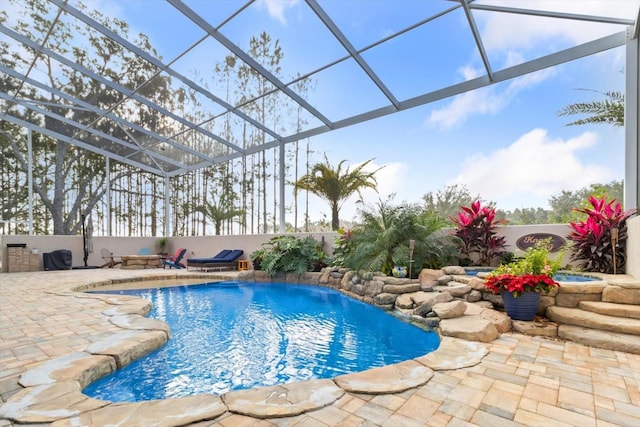 view of swimming pool featuring a patio area, pool water feature, and glass enclosure