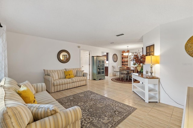 living room with light tile patterned floors, a textured ceiling, and a notable chandelier