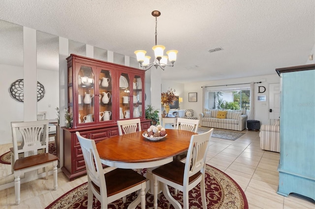 dining room featuring light tile patterned floors, a textured ceiling, and a chandelier