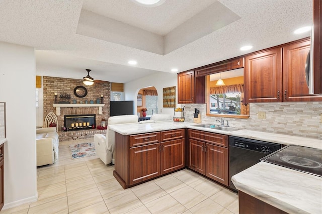 kitchen featuring kitchen peninsula, a brick fireplace, ceiling fan, sink, and dishwasher