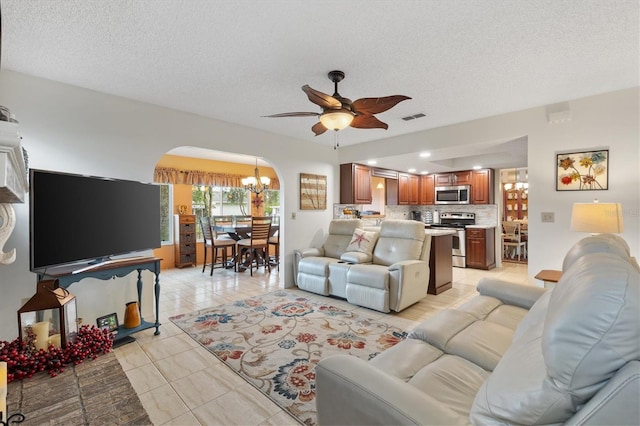 tiled living room with a textured ceiling and ceiling fan with notable chandelier