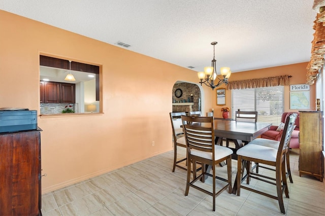 dining area featuring a fireplace, a textured ceiling, and a notable chandelier