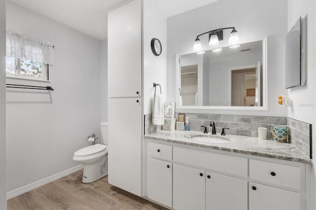 bathroom featuring tasteful backsplash, toilet, vanity, and hardwood / wood-style flooring