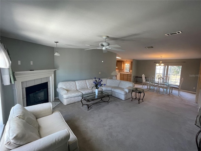 living room with ceiling fan with notable chandelier, carpet floors, and a fireplace