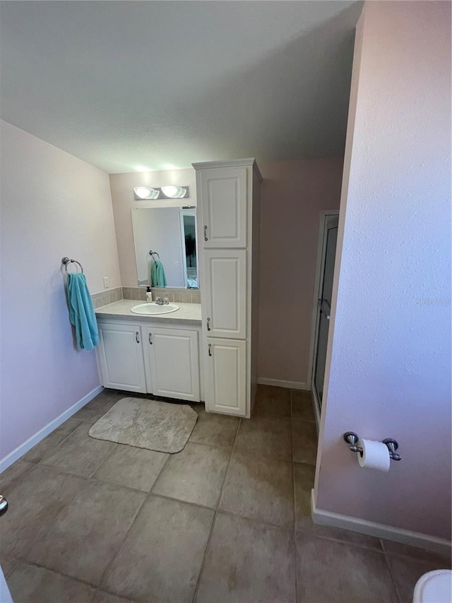 bathroom featuring tile patterned floors, a shower with door, and vanity