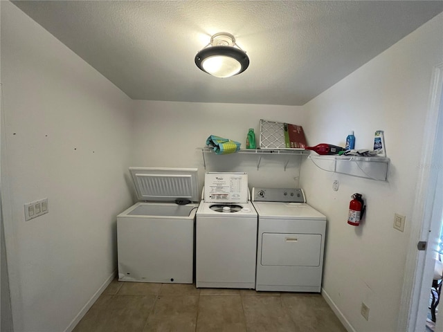 laundry room with washer and clothes dryer, light tile patterned floors, and a textured ceiling