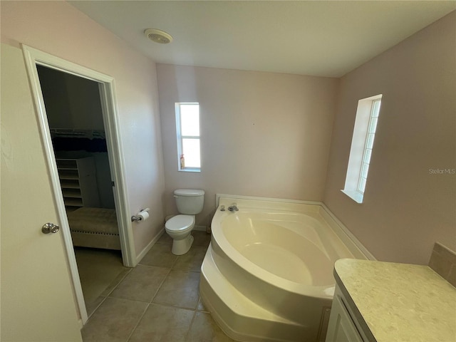 bathroom with tile patterned flooring, a bath, vanity, and toilet