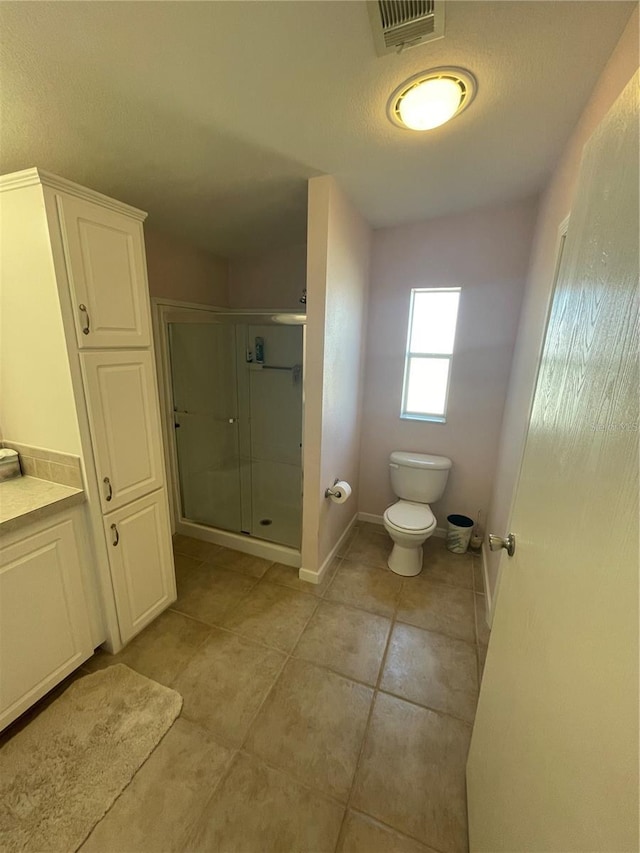 bathroom with tile patterned flooring, vanity, an enclosed shower, and toilet