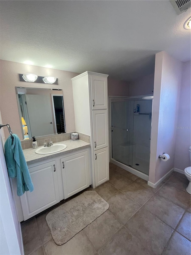 bathroom with tile patterned flooring, vanity, toilet, and a shower with door