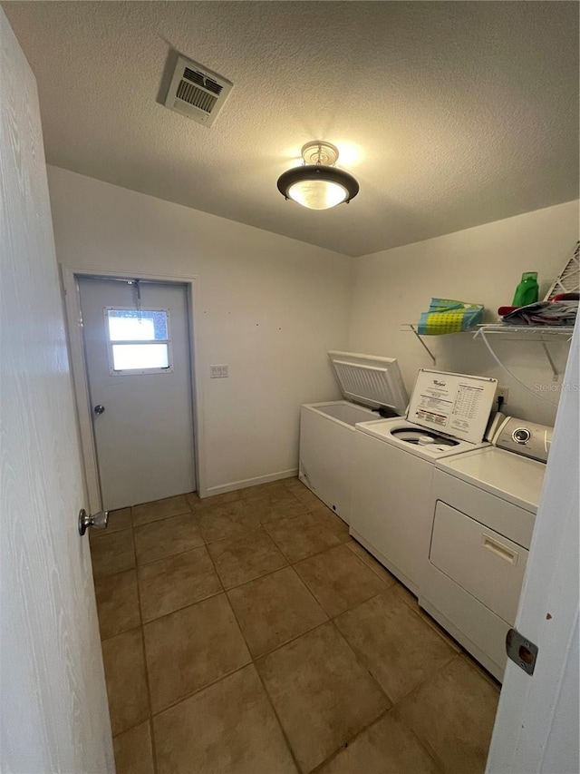 washroom with tile patterned floors, independent washer and dryer, and a textured ceiling