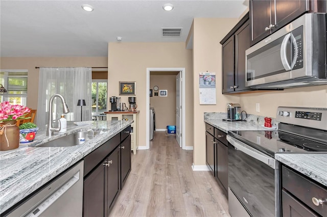 kitchen featuring dark brown cabinetry, sink, light stone counters, plenty of natural light, and stainless steel appliances