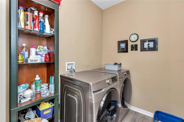 clothes washing area featuring washing machine and dryer and light hardwood / wood-style floors