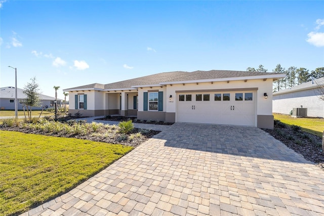 view of front of house featuring a front lawn, a garage, and central AC