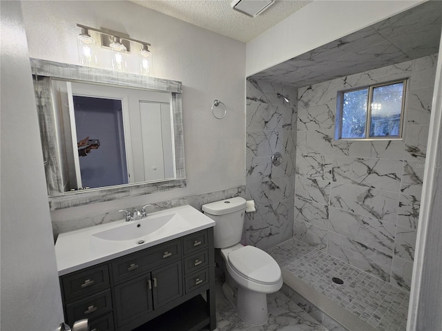 bathroom featuring toilet, vanity, a textured ceiling, and tiled shower