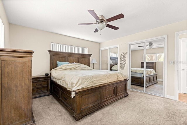 bedroom with two closets, ceiling fan, and light colored carpet