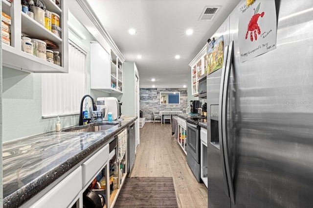 kitchen with light wood-type flooring, stainless steel appliances, white cabinetry, and sink