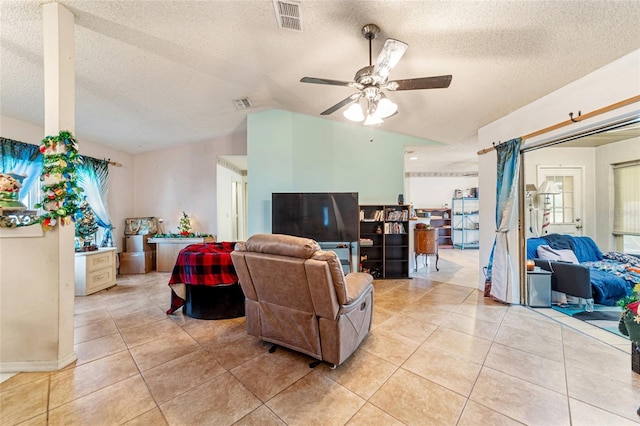 tiled living room featuring lofted ceiling, ceiling fan, and a textured ceiling