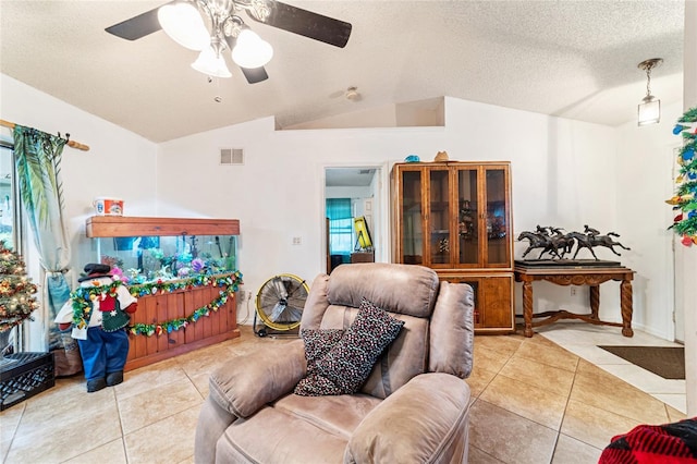 tiled living room with a textured ceiling, ceiling fan, and lofted ceiling