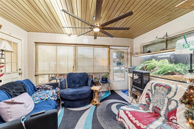 sunroom with a wood stove, ceiling fan, and wood ceiling