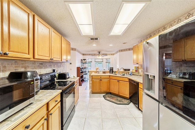 kitchen with black appliances, sink, ceiling fan, light tile patterned flooring, and kitchen peninsula