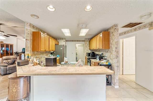 kitchen with kitchen peninsula, appliances with stainless steel finishes, and a textured ceiling