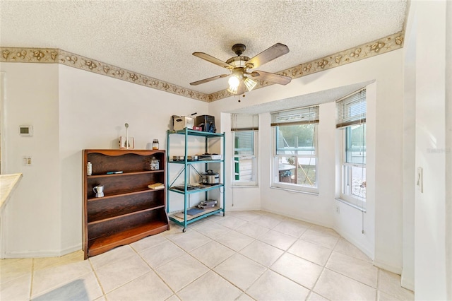 tiled empty room with ceiling fan and a textured ceiling