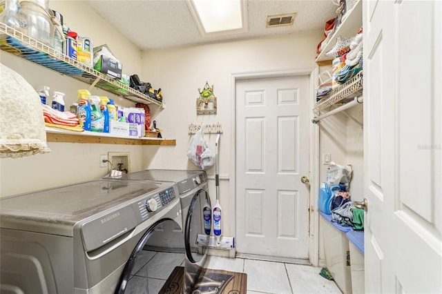 laundry area featuring light tile patterned flooring, separate washer and dryer, and a textured ceiling