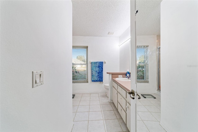 bathroom featuring tile patterned floors, walk in shower, a textured ceiling, vanity, and toilet