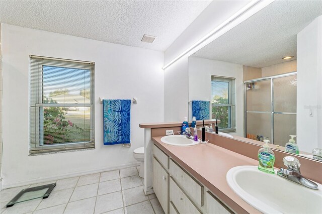 bathroom with tile patterned floors, a textured ceiling, toilet, a shower with door, and vanity