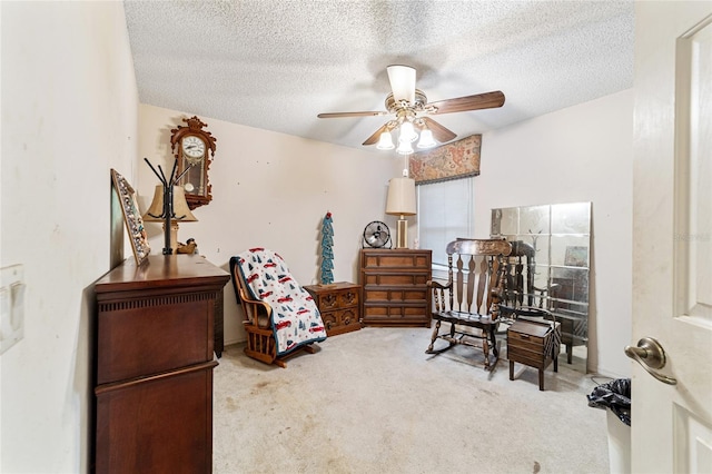 living area with ceiling fan, carpet floors, and a textured ceiling