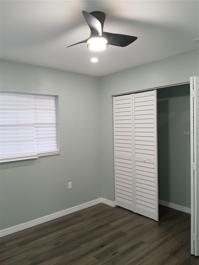 unfurnished bedroom with a closet, ceiling fan, and dark wood-type flooring