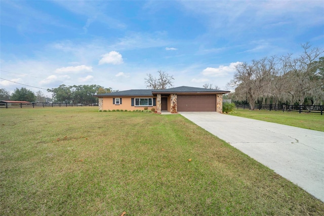 ranch-style house featuring a front lawn, a rural view, and a garage