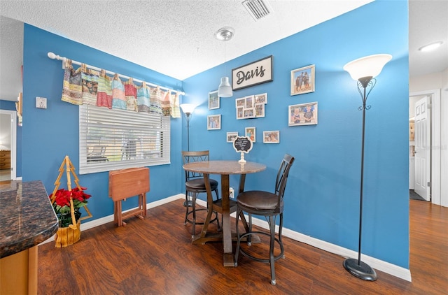 dining space with dark hardwood / wood-style flooring and a textured ceiling