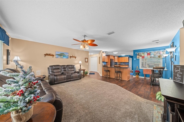 living room featuring ceiling fan, dark hardwood / wood-style flooring, and a textured ceiling